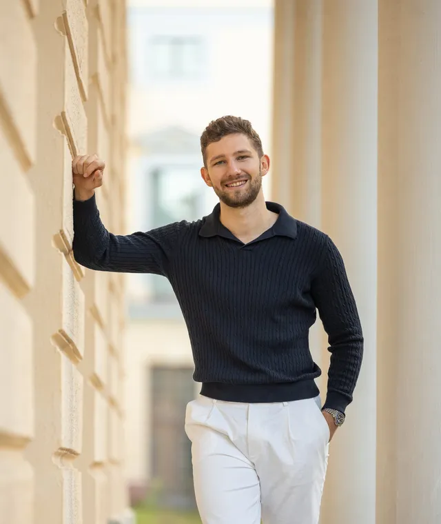 Daniel Wegener lächelnd, draußen an eine Wand gelehnt